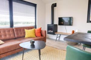 a living room with a couch and a table at Cube la Mer 4 in Olburgen