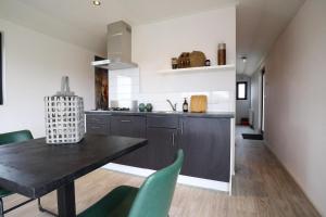 a kitchen with a black table and green chairs at Cube la Mer 4 in Olburgen +68 photos