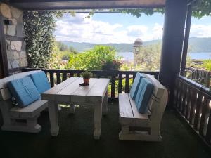 a wooden table and bench on a porch with a view at Deluxe House Glavatarski Han in Glavatartsi
