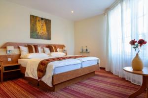 a bedroom with a large bed and a vase of flowers at Boutique Hotel Wolfsburg in Wolfsburg