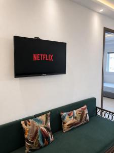 a television on a wall above a green couch at Appartement MIRAMAR in Martil