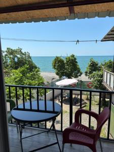 a balcony with a table and chairs and the ocean at Kety House in Makhinjauri