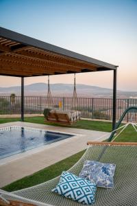 a patio with a hammock next to a swimming pool at Briaa Wellness Resort Hotel Gilboa - Adults Only in Maalé-Hagilbo‘a