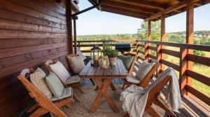 a wooden deck with a table and chairs at Jotwingia - Domki z Widokiem in Stare Juchy