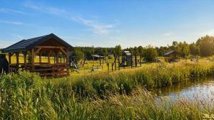 a park with a playground next to a river at Jotwingia - Domki z Widokiem in Stare Juchy