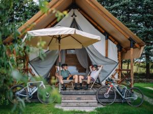 two people sitting in chairs in a tent with bikes at Sunrise Lake Area in Unterlibitsch +6 photos
