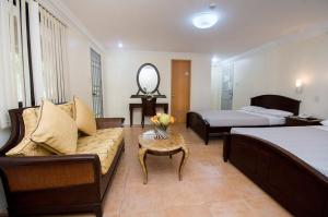 a hotel room with a couch and a bed at El Centro Beach Resort Boracay in Boracay