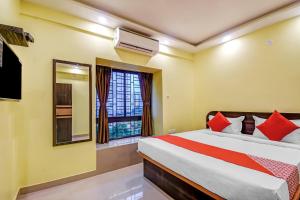 a bedroom with a bed with red pillows and a window at Hotel O DOWNTOWN INN in Kolkata +20 photos