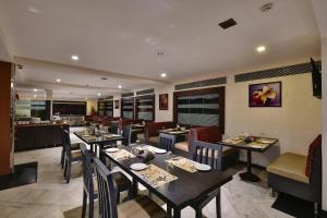 a dining room with tables and chairs in a restaurant at Click Hotel Yuvraj in Surat