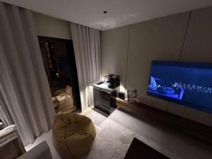 a living room with a flat screen tv and a chair at Copper Living in Muscat