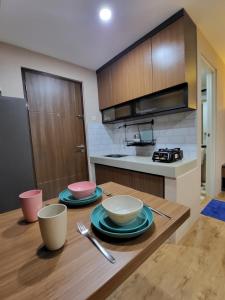 a kitchen with a wooden table with bowls and plates on it at SkyBreeze Sentraland in Medan