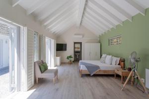 a bedroom with a bed and a chair in a room at The Barn Style Cottage in Cape Town