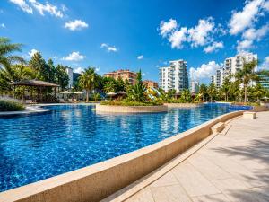 a large swimming pool with palm trees and buildings at Maxihomes Snitch in Kemerağzı