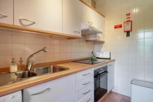 a kitchen with white cabinets and a sink at bwelcome aroeira beach & golf in Charneca +35 photos