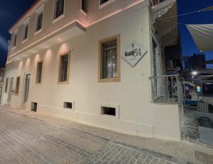 a white building with a sign on the side of it at Ralli 34 ROOMS&APTS in Chios