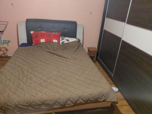 a bed with a brown blanket and a red pillow at Marinel in Vršac