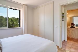 a bedroom with a white bed and a window at bwelcome aroeira beach & golf in Charneca