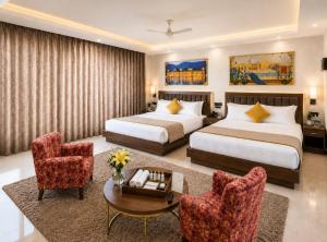 a hotel room with two beds and a table and chairs at Lime Tree Hotel & Banquet Jal Mahal Jaipur in Jaipur