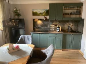 a kitchen with green cabinets and a wooden table at Haus Louise in Reit im Winkl