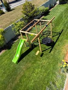 a wooden play structure with a slide in the grass at VILLA MEGER in Veľký Meder +23 photos