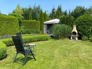 a black chair sitting in a yard with a grill at Dworek na Polance in Wrzosowo