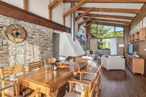 a dining room and living room with a stone wall at Pirin Golf Villa in Bansko