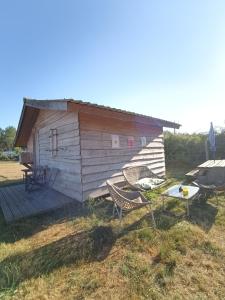 a small wooden cabin with two chairs and a table at Gîte - La Ferme à la Plage in Le Porge