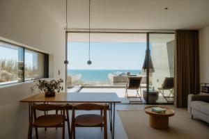 a living room with a table and chairs and a view of the ocean at oceanHUTS Coxos Adults Only from age 14 in Ericeira