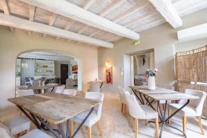 a dining room with wooden tables and white chairs at Boutique Hôtel La Villa Montesquieu & sa piscine in Laudun