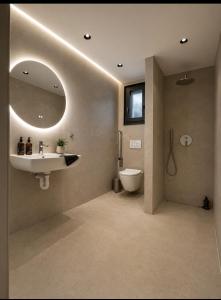 a bathroom with a sink and a toilet and a mirror at Estia Luxury Suites & Spa in Platamonas
