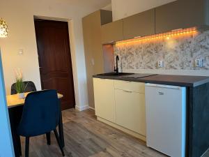 a kitchen with a counter and a table with a blue chair at Apartamenty Harnaś in Rytro