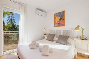 a white bedroom with a large white bed and a window at Mora Beach in Tarragona +31 photos