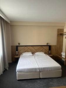 a bedroom with a white bed with two tables at Хотел Аква Варвара in Varvara +29 photos