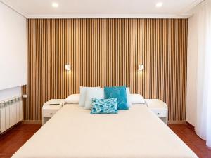 a bedroom with a large bed with blue pillows on it at Hostal Bellas in Ávila
