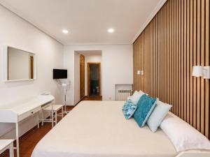 a bedroom with a bed with a desk and a sink at Hostal Bellas in Ávila +13 photos