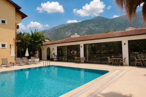 a swimming pool in front of a building with a mountain at Güneş Boutique Hotel - Oludeniz in Oludeniz