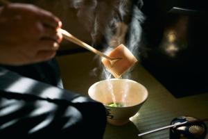 a person is stirring a bowl with a chopstick at 一組限定の宿 季の間 Private Traditional House & Tea Experience in Nagano in Iida