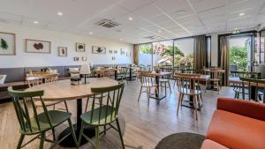 a restaurant with wooden tables and chairs and windows at Campanile NATURE - Bollene in Bollène