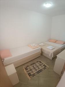a white room with two beds and a rug at Pet Friendly Apartment Ground Floor in Petrovac na Moru