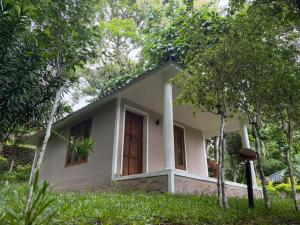 a small white house in the middle of trees at Sumeru valley vagamon in Idukki