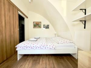 a bedroom with a white bed and a staircase at Apartmány u komína in Terezín