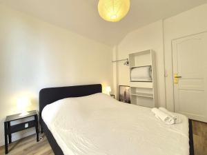a bedroom with a white bed and a lamp at Vilnius - Confort familial in Reims