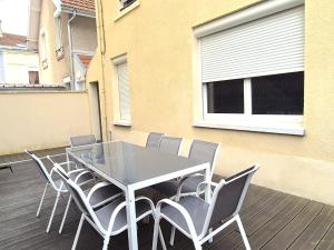 a glass table and chairs on a deck with a building at Vilnius - Confort familial in Reims
