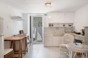 a kitchen with white cabinets and a table and chairs at Vasso Galati House in Vaia +16 photos