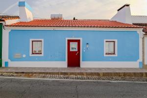 a blue and white building with a red door at Casa dos Manos in Barbacena
