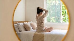 a woman sitting on a bed in front of a mirror at Pocheon Skygaram Pension in Pocheon