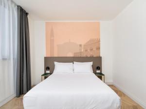 a bedroom with a white bed and a wall mural at B&B HOTEL Catania Bellini in Catania
