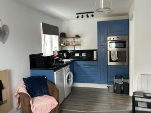 a kitchen with blue cabinets and a washing machine at Captivating 1-Bed Apartment in Hednesford in Cannock