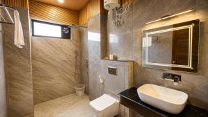 a bathroom with a sink and a toilet and a mirror at Dharamshila Retreat in Chakrāta