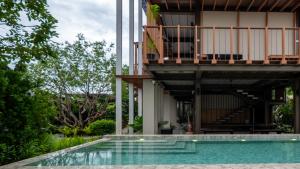 a house with a balcony and a swimming pool at Baanna Place in Ban Na